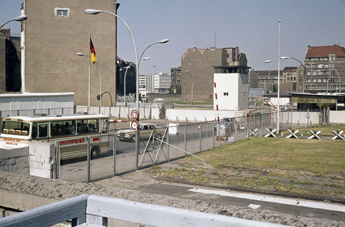 Der DDR-Grenzübergang, im Zentrum der Wachturm mitten auf der Straße, daneben Panzersperren.