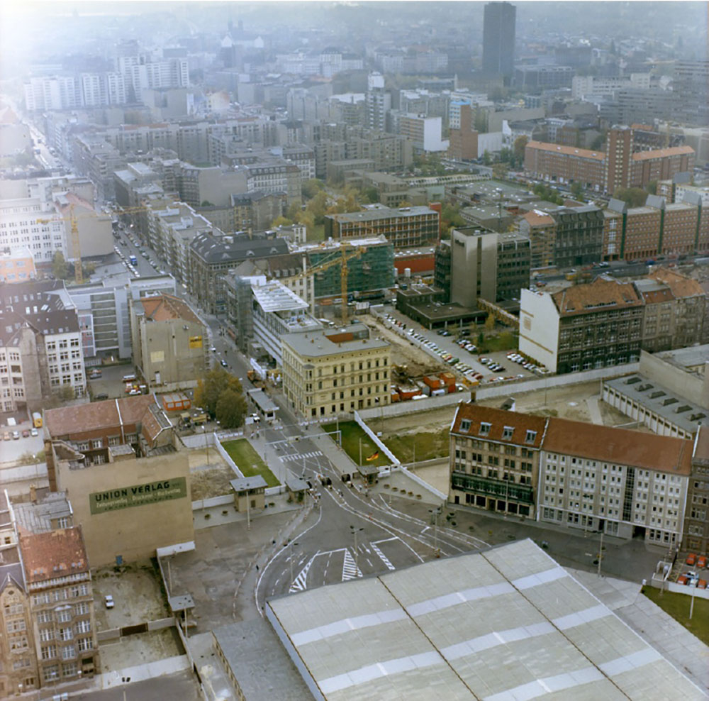 Luftbild Richtung West-Berlin, der DDR-Grenzübergang ist vollständig von einer großen Halle überdacht.