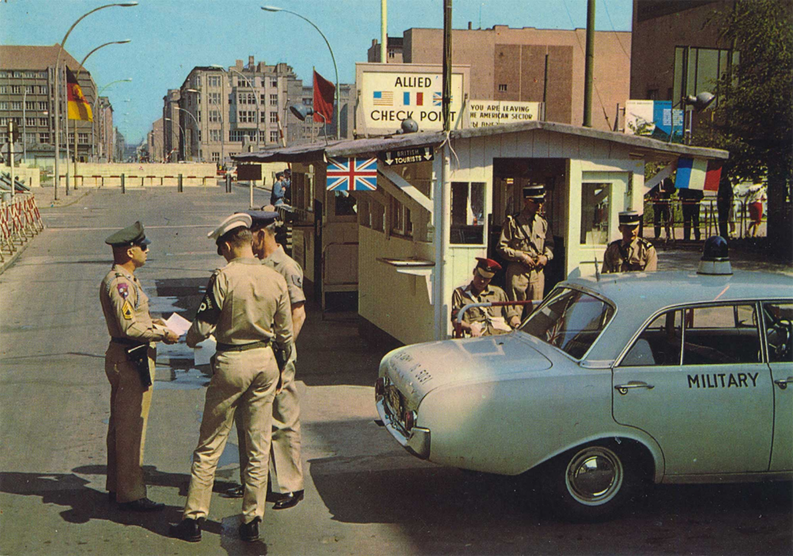 US military police officers in front of the Allied Checkpoint Charlie, with the GDR border installations in the background.