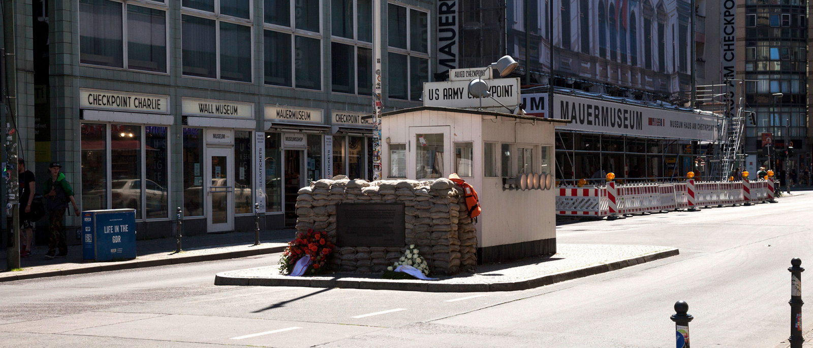 The Allied control booth on Friedrichstrasse, rebuilt in 2001, with a pile of sandbags and two bouquets of flowers in front of it.